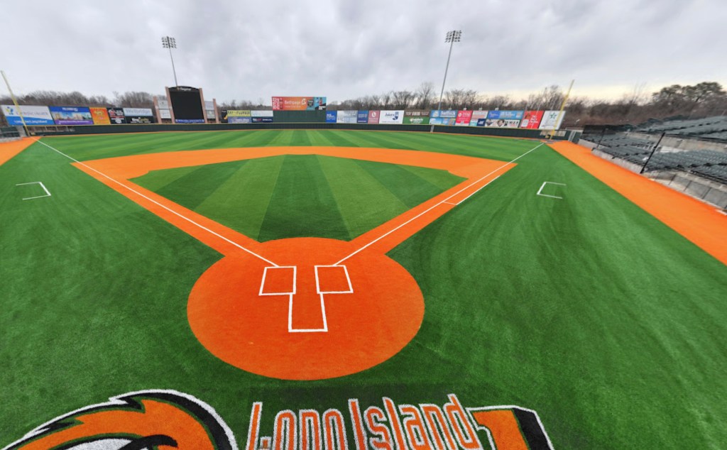 Baseball field with green turf and orange dirt.